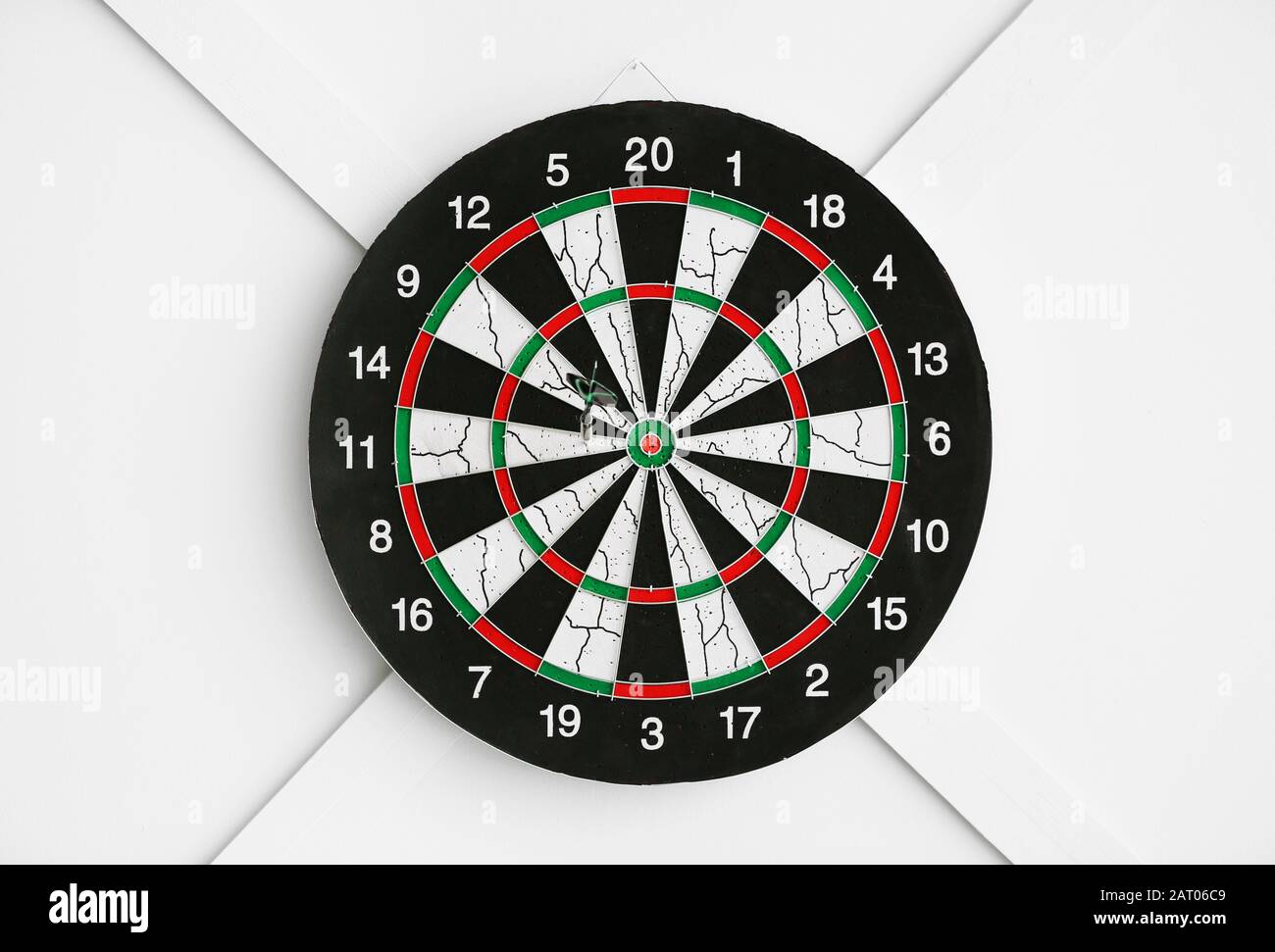 Dartboard hanging on light wall Stock Photo