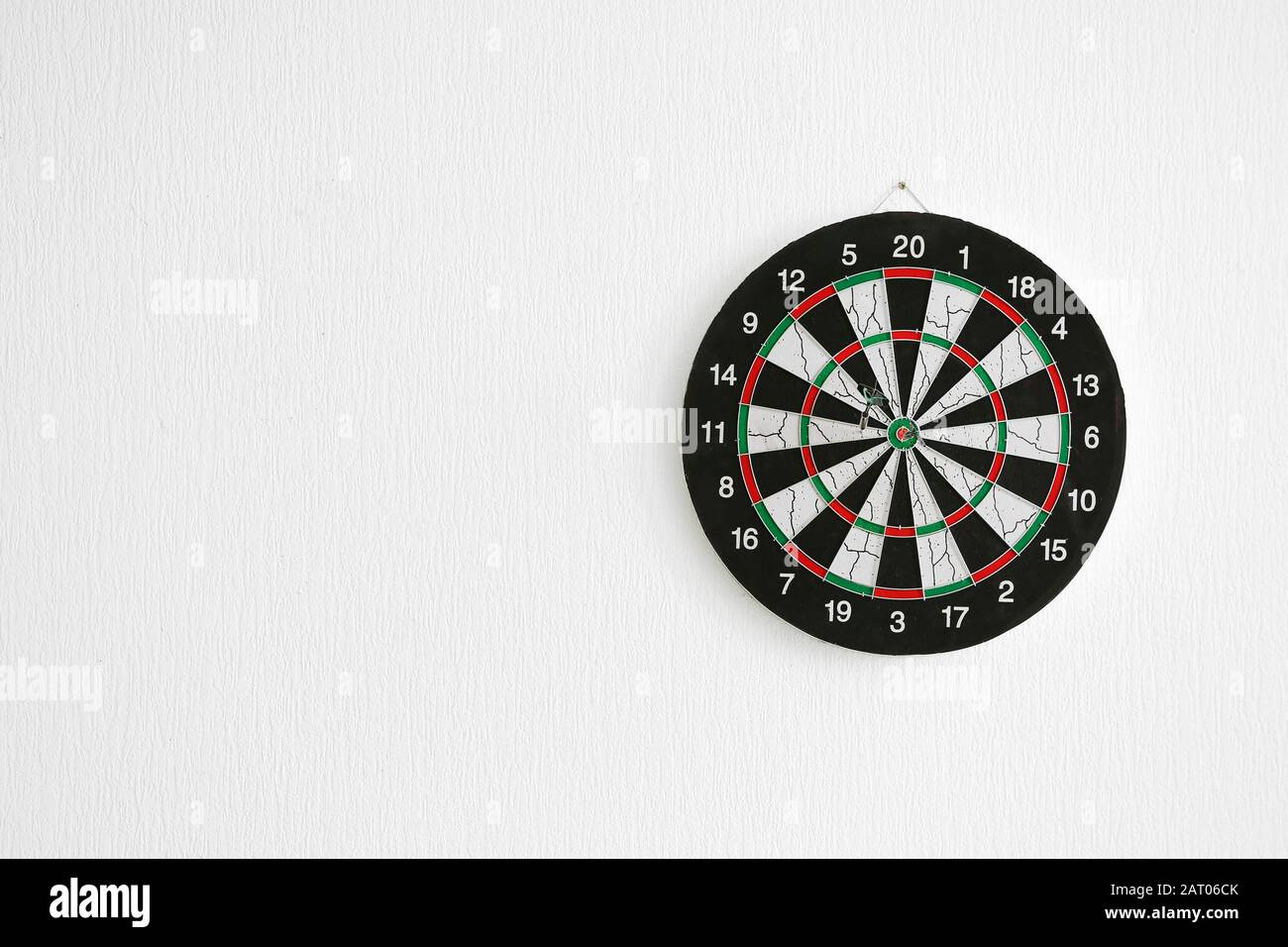 Dartboard hanging on light wall Stock Photo
