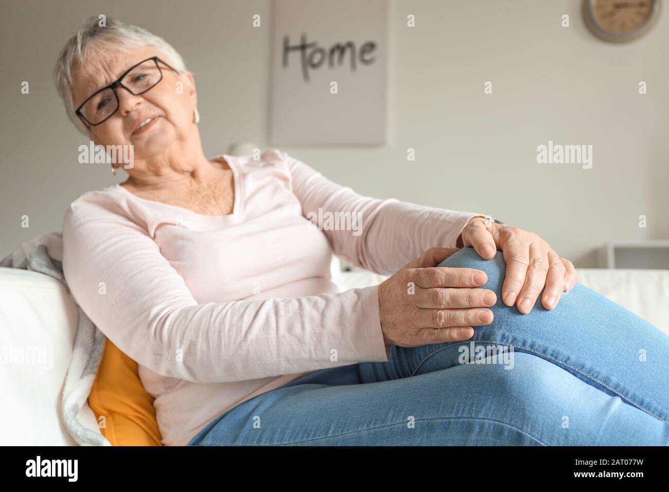 Senior woman suffering from pain in knee at home Stock Photo - Alamy