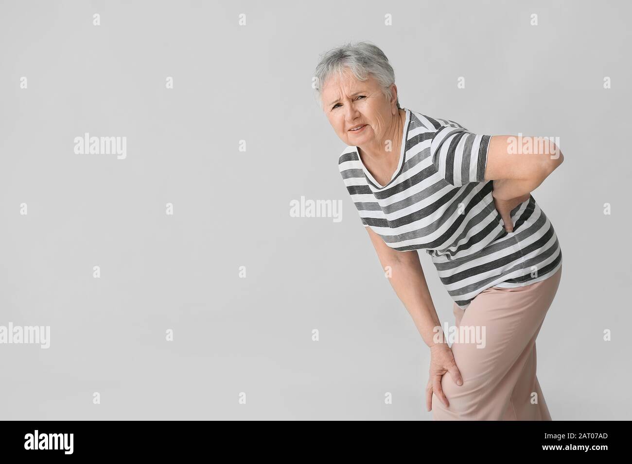 Senior woman suffering from back pain on grey background Stock Photo ...