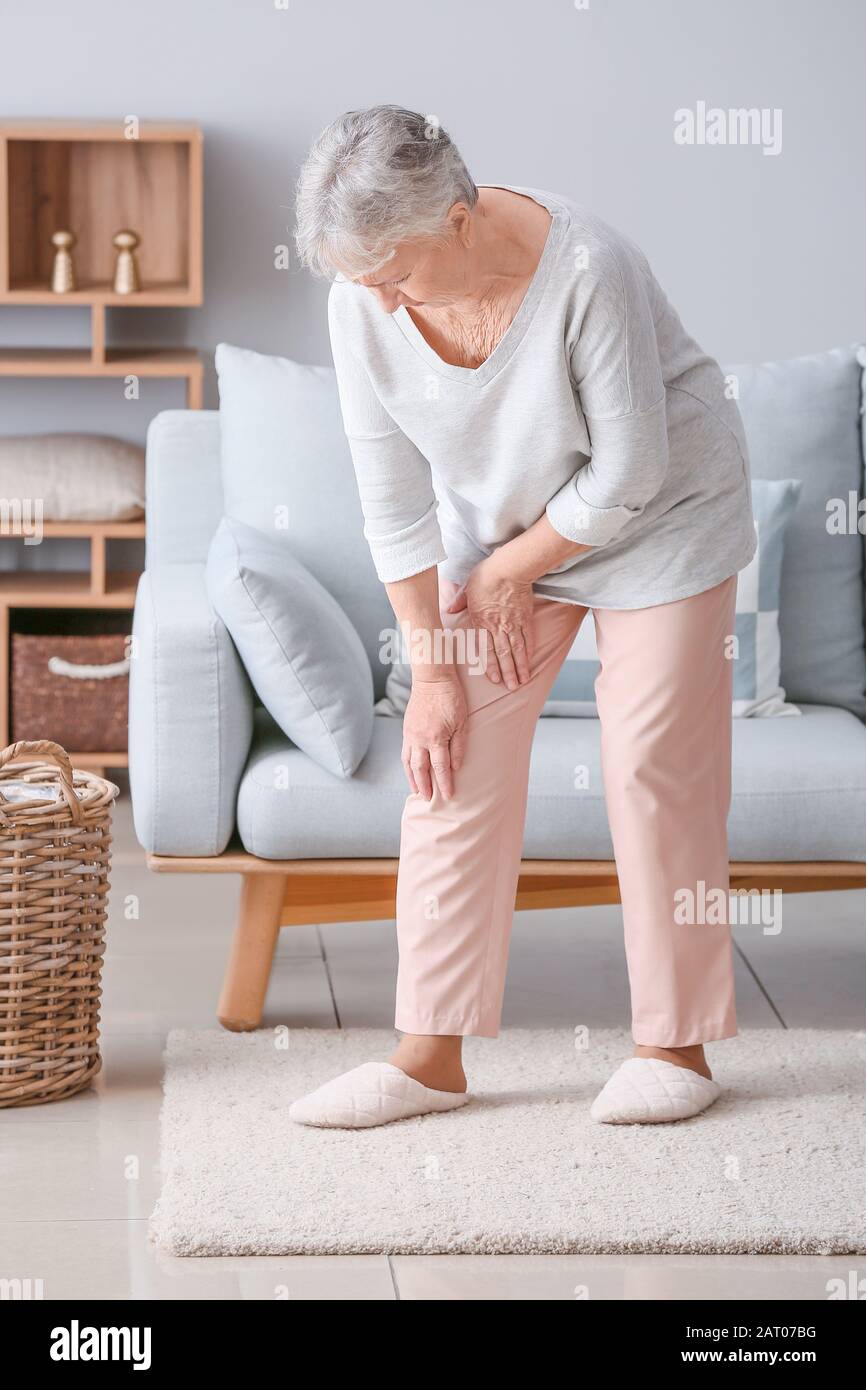 Senior woman suffering from pain in knee at home Stock Photo - Alamy