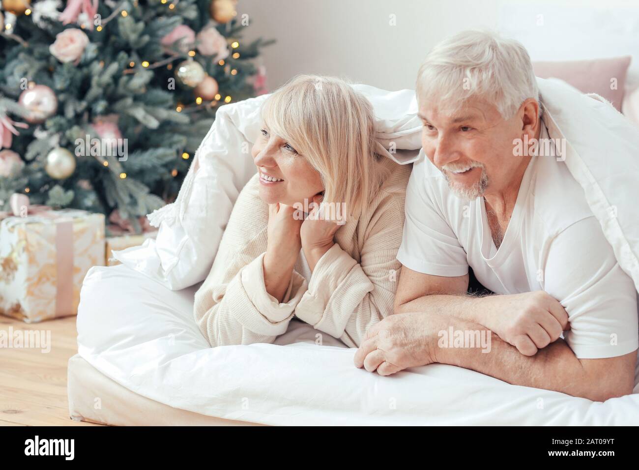 Happy mature couple lying under blanket in bed Stock Photo - Alamy