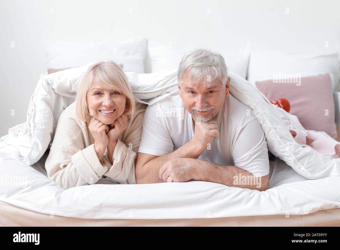 Happy mature couple lying under blanket in bed Stock Photo - Alamy