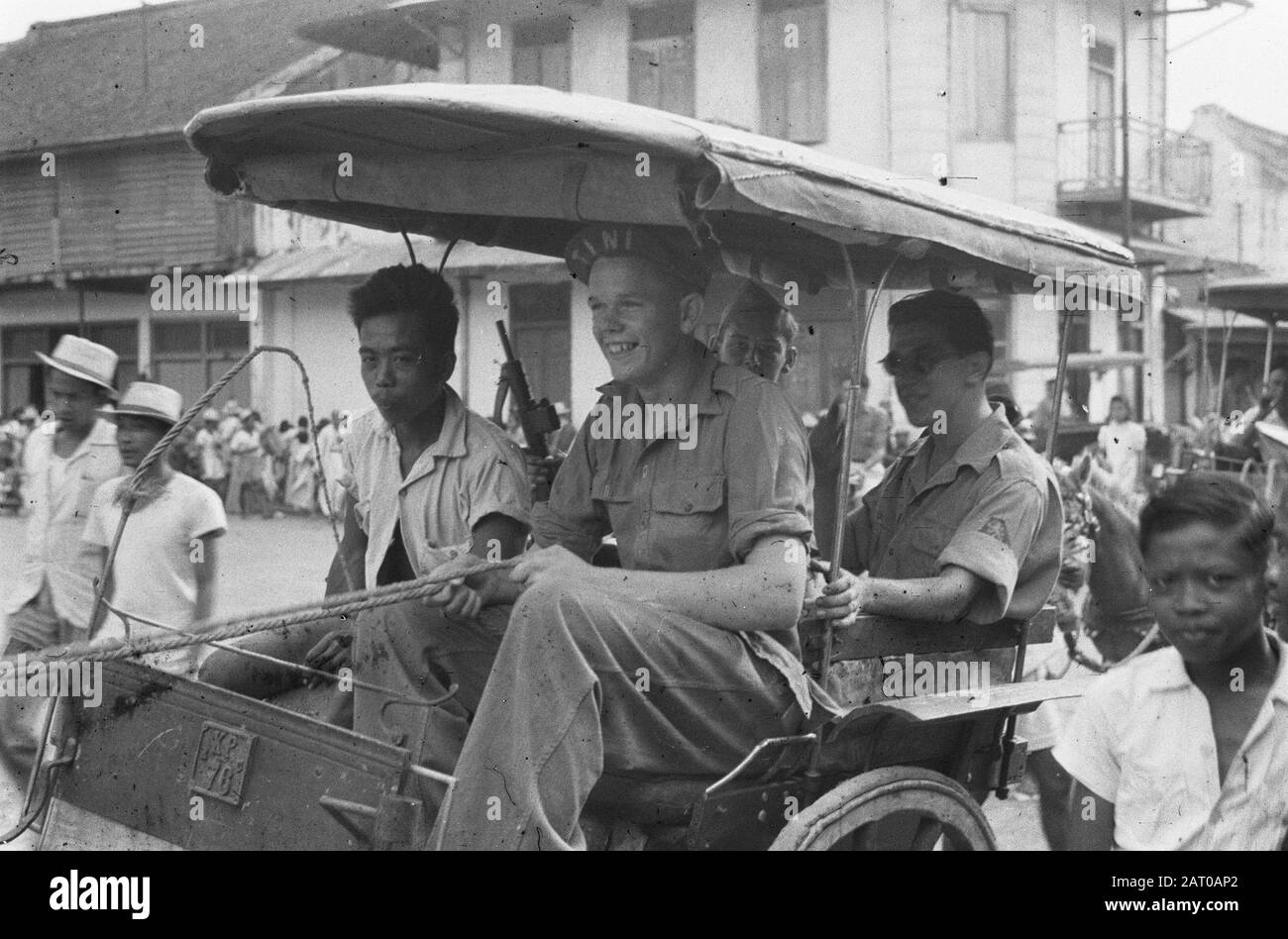 Cheribon. Parade, various topics [Tjikampek]  Three Dutch soldiers in a dokar Annotation: The front soldier wears a cap called Tini. The soldier in the back carries a stengun (without patternholder) Date: October 1947 Location: Indonesia, Dutch East Indies Stock Photo