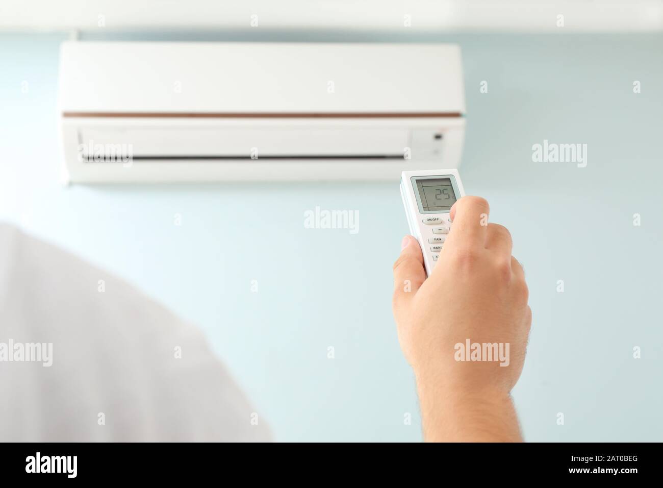 Young man switching on air conditioner at home Stock Photo Alamy