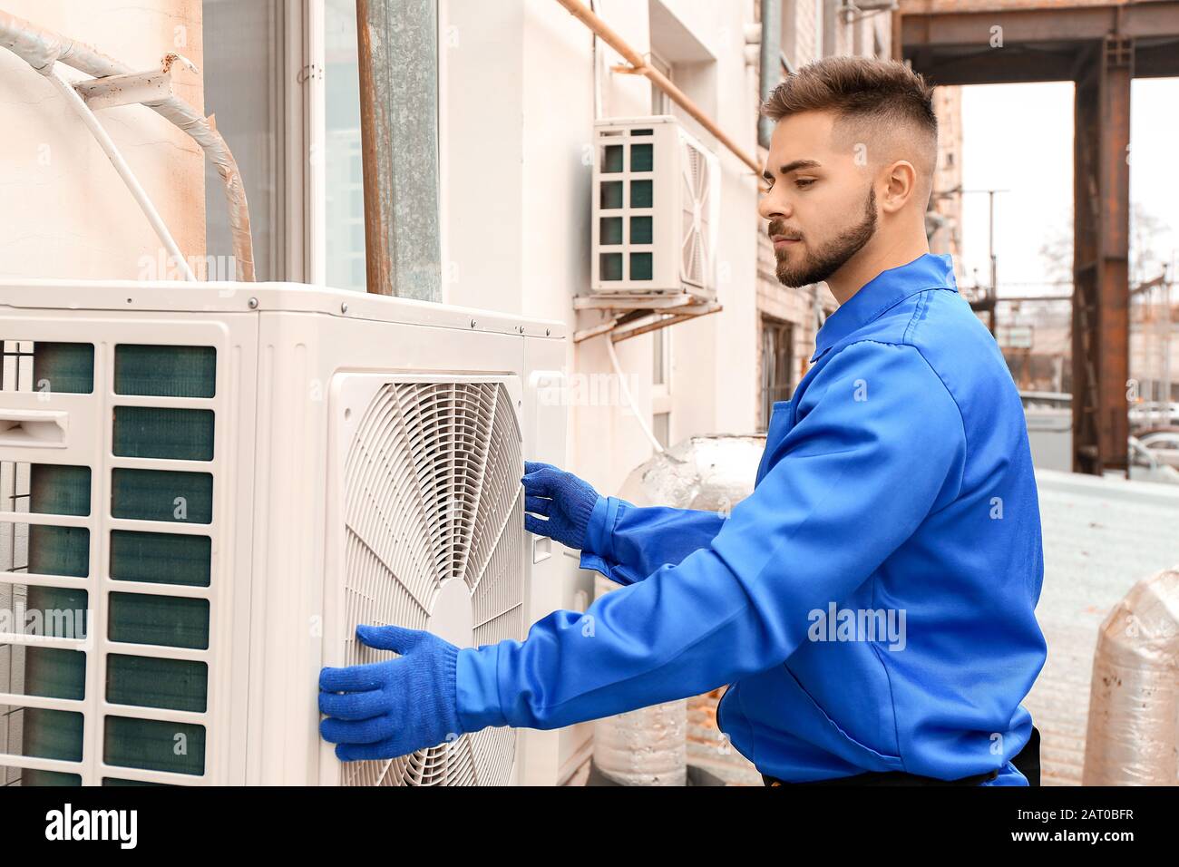 Male technician installing outdoor unit of air conditioner Stock Photo