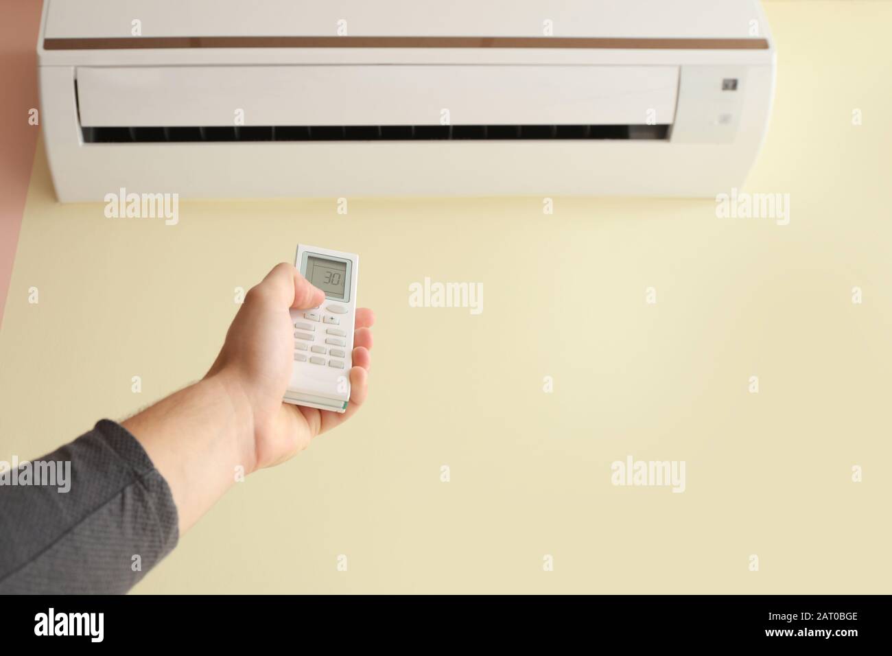 Young man switching on air conditioner at home Stock Photo Alamy
