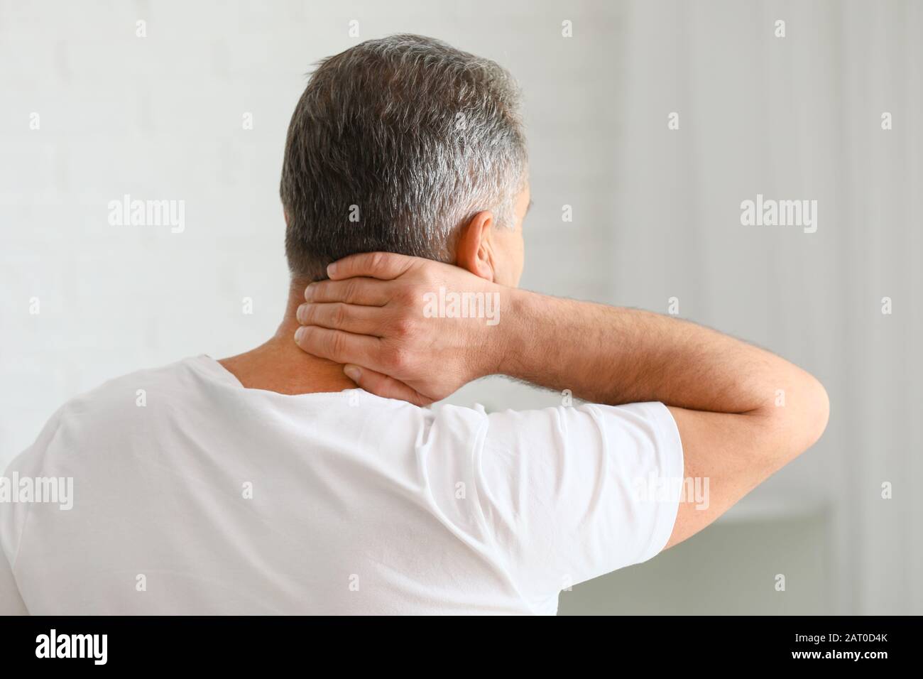 Mature man suffering from neck pain at home Stock Photo - Alamy