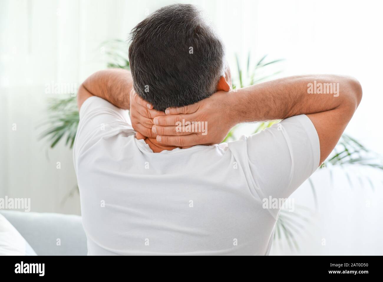 Mature man suffering from neck pain at home Stock Photo - Alamy