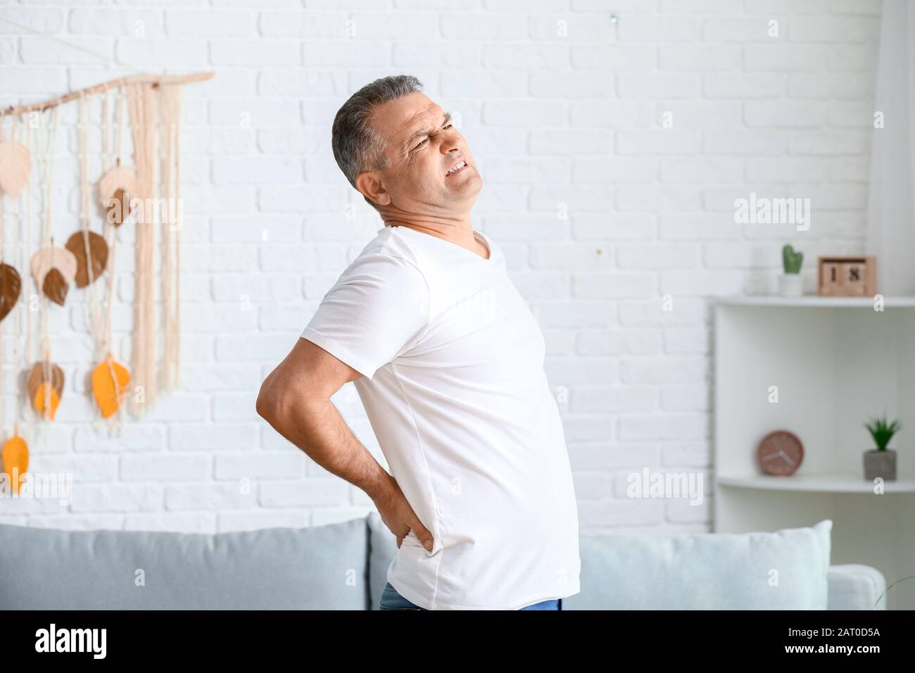 Mature man suffering from back pain at home Stock Photo - Alamy
