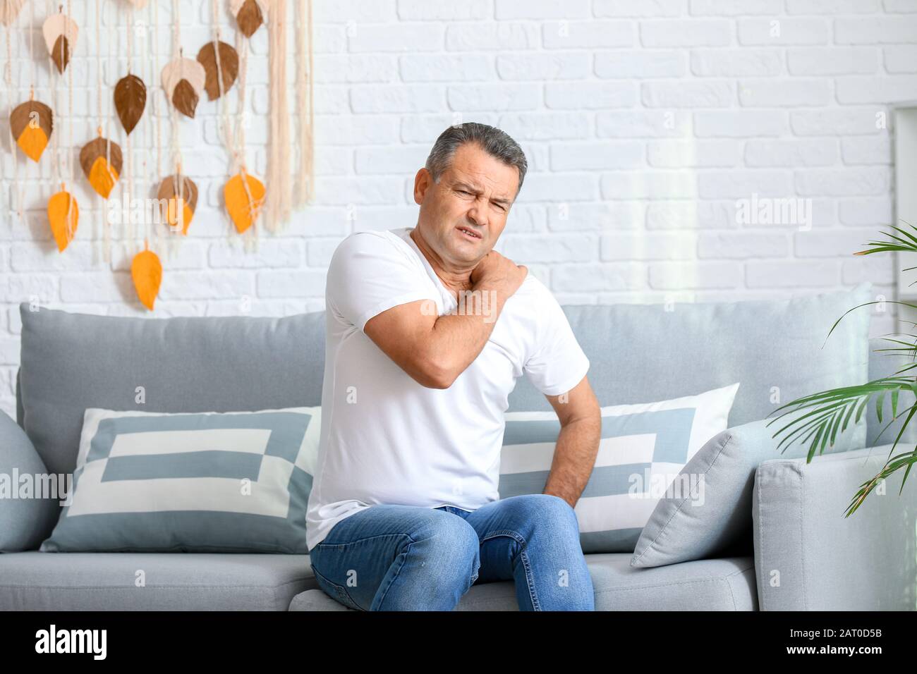 Mature man suffering from pain in shoulder at home Stock Photo - Alamy