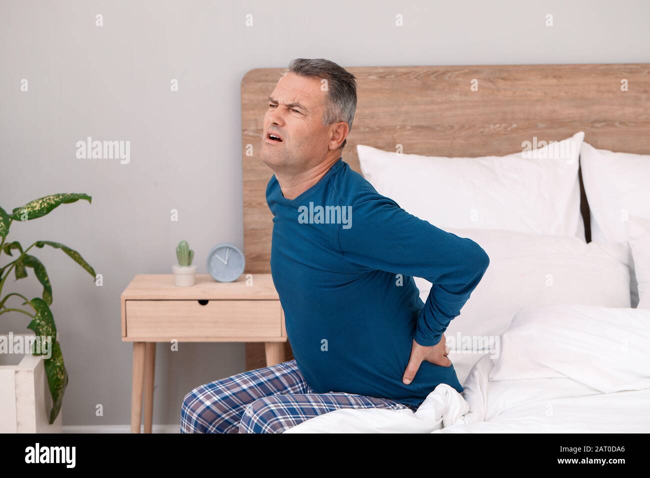 Mature man suffering from back pain in bedroom Stock Photo - Alamy