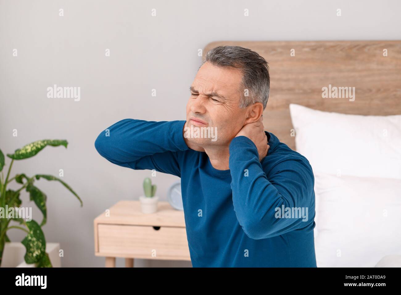 Mature man suffering from neck pain in bedroom Stock Photo - Alamy