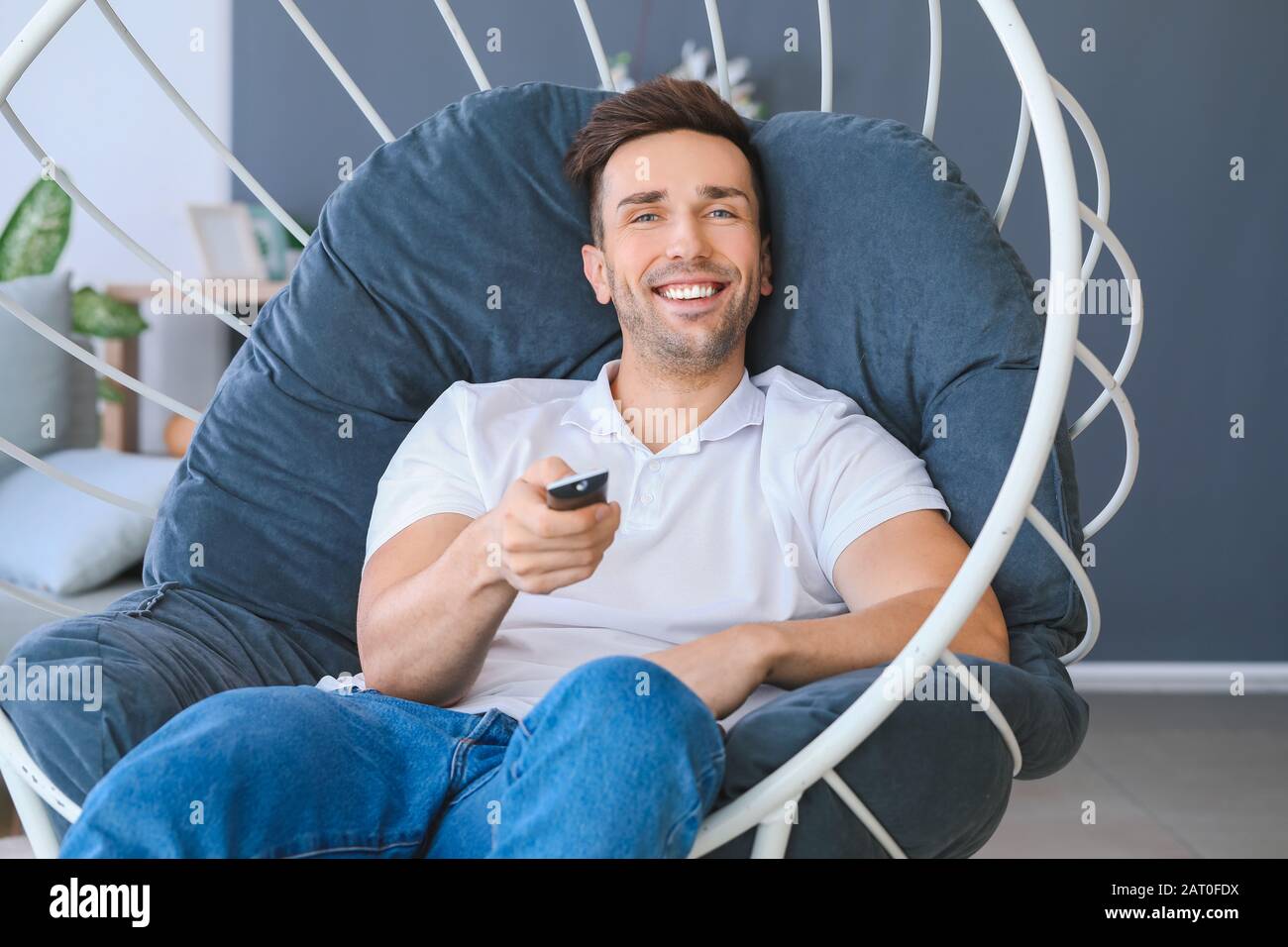 Handsome man watching TV while sitting in armchair at home Stock Photo