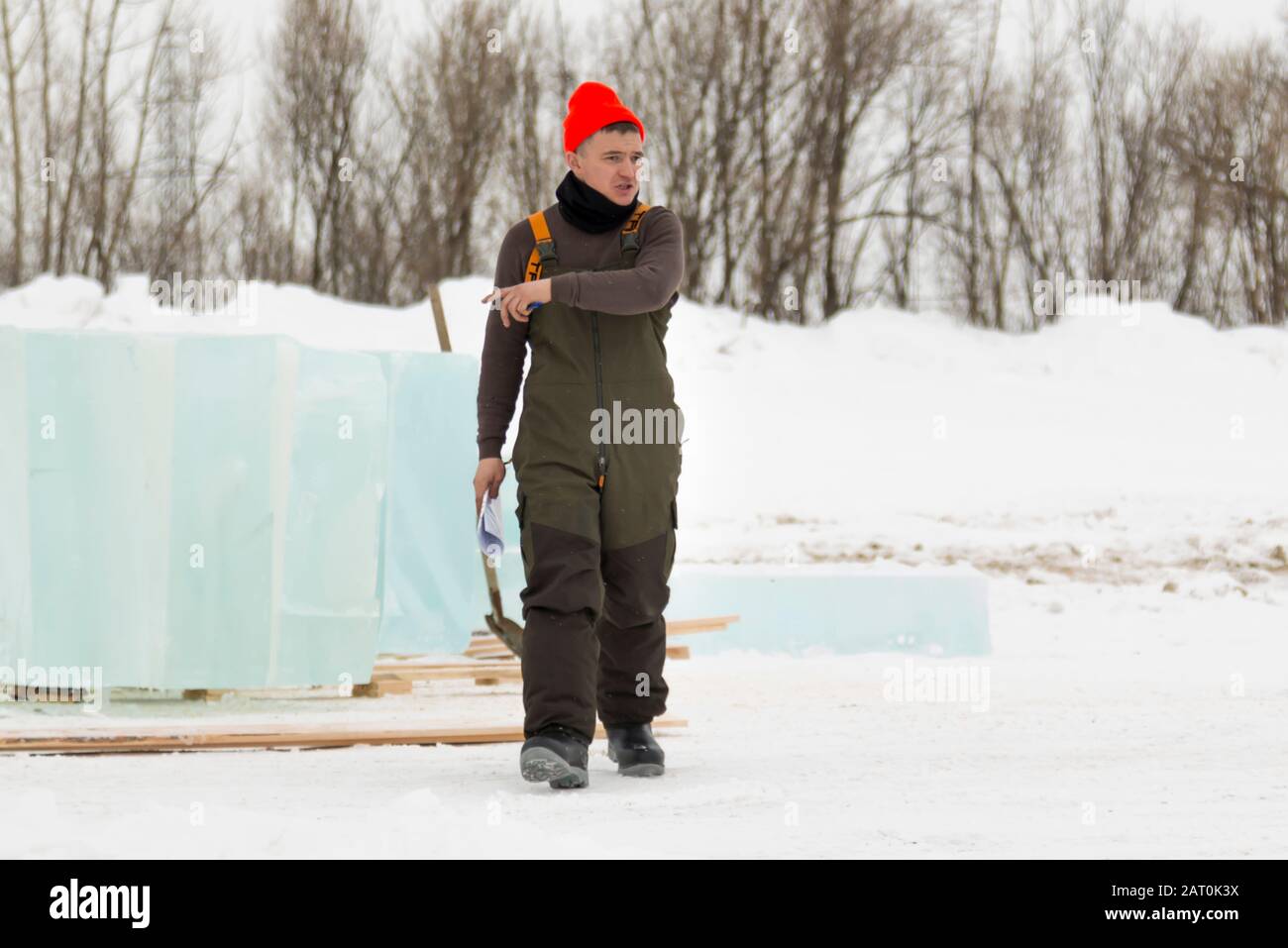 Worker in a red knitted hat is walking on the assembly site Stock Photo