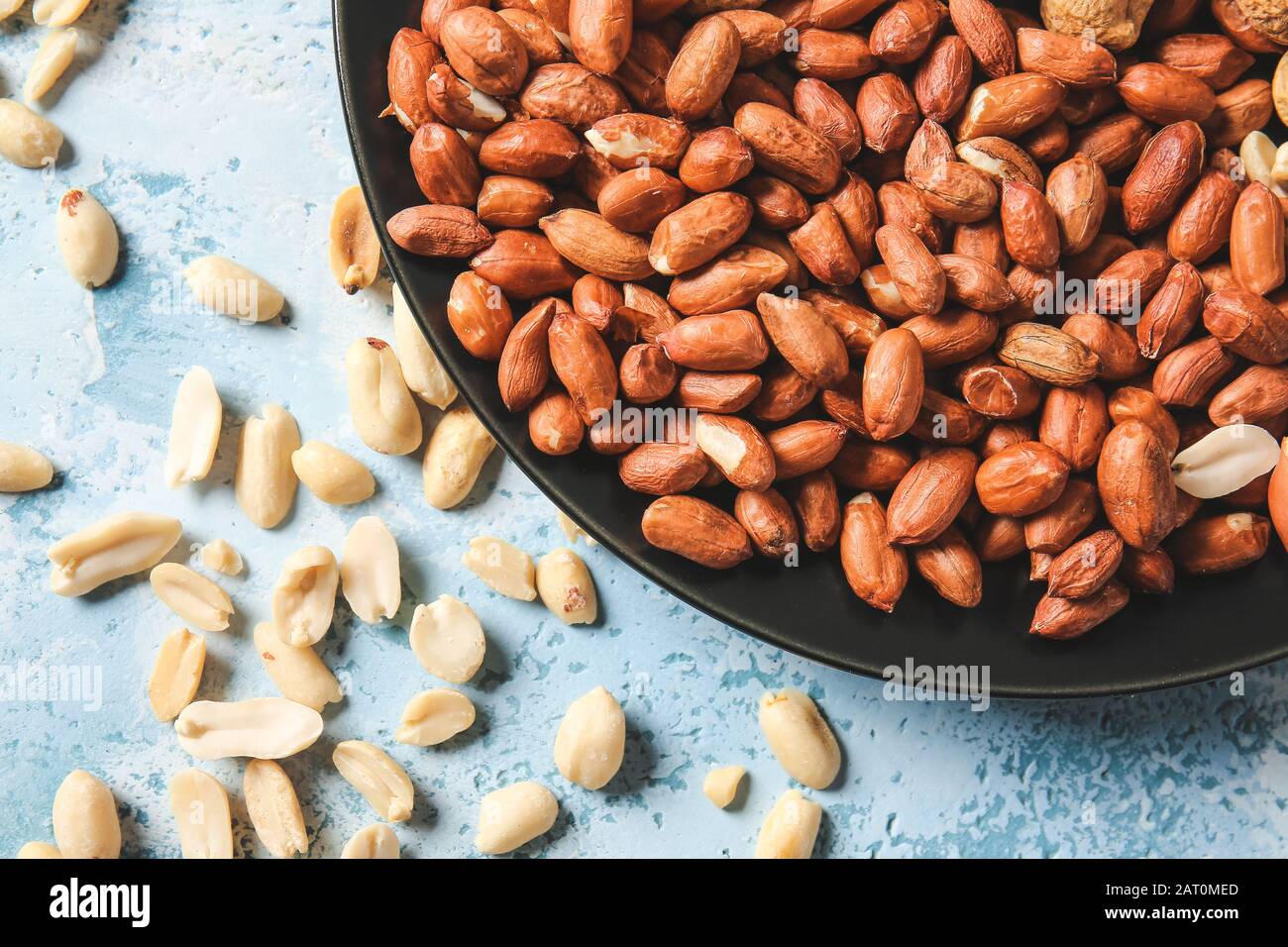 Plate with peanuts on color background Stock Photo