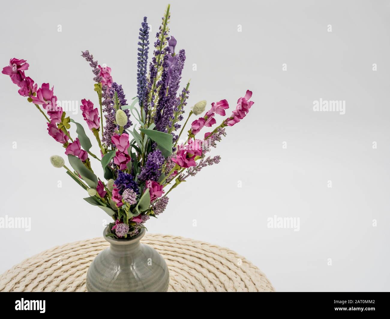 Purple And Pink Artificial Wildflowers In A Gray Ceramic Vase And An Off White Round Placemat Stock Photo Alamy