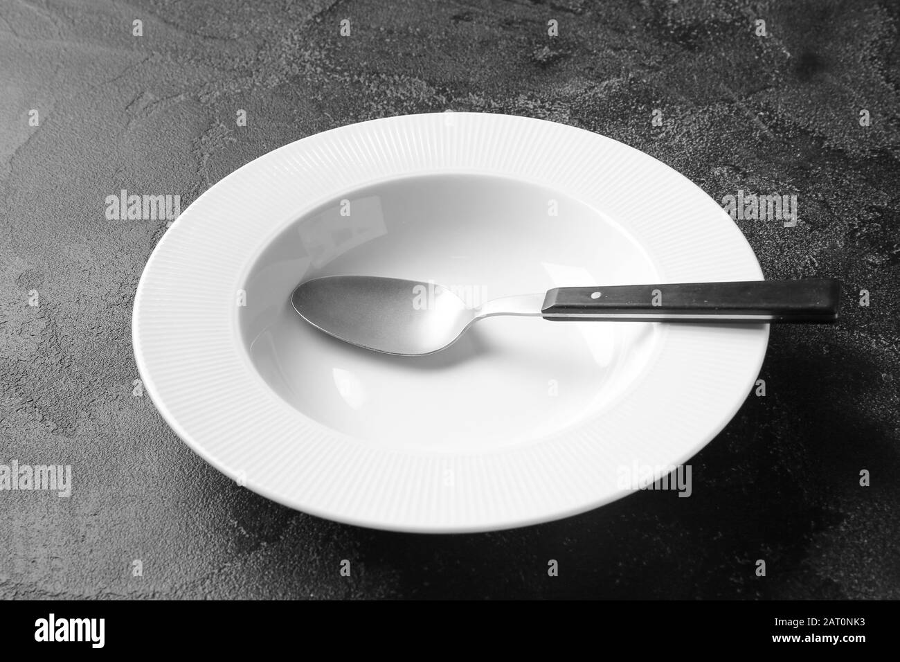 Empty plate and spoon on dark background Stock Photo - Alamy