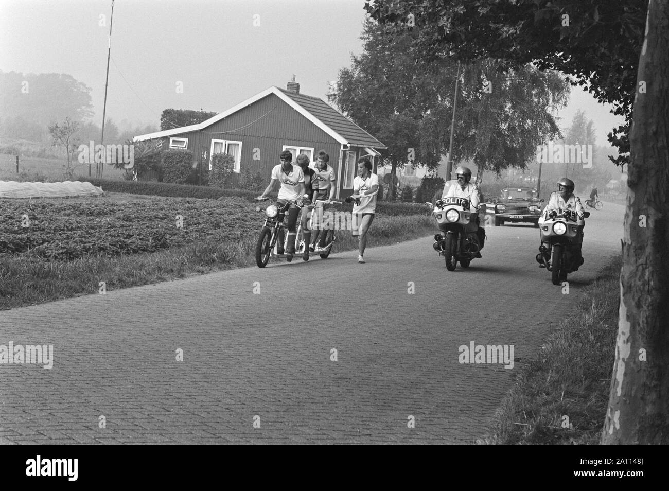 Autoped-tour to Utrecht in Breda started (fourth time)  A four-person autoped during the autoped-tour from Breda to Utrecht accompanied by two motorcyclists Date: 9 September 1981 Location: Breda, Noord-Brabant, Utrecht (province), Utrecht (city) Keywords: autopeds, motorcycles, travel, students Stock Photo