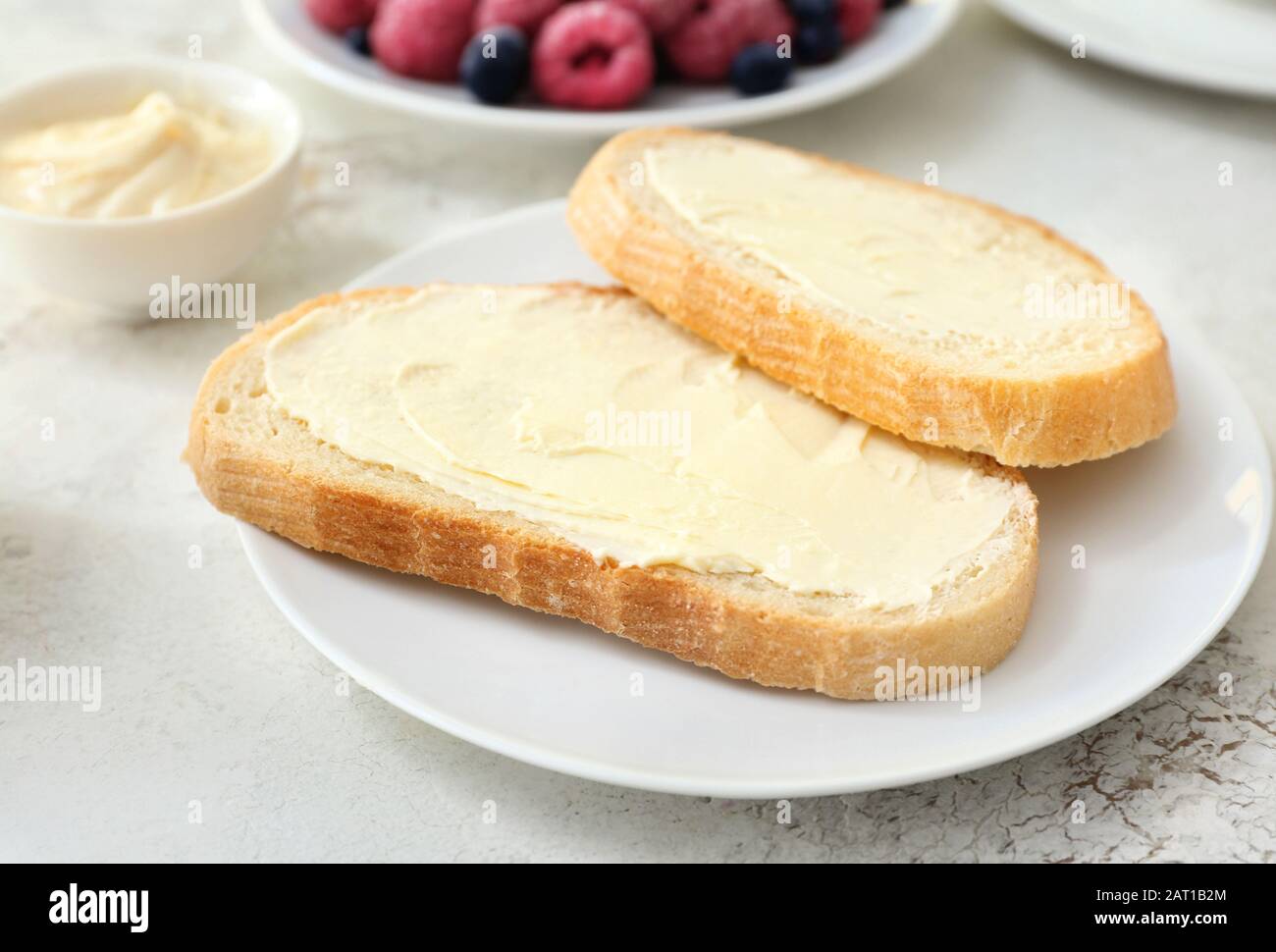 Plate with slices of bread and fresh butter on white background Stock ...