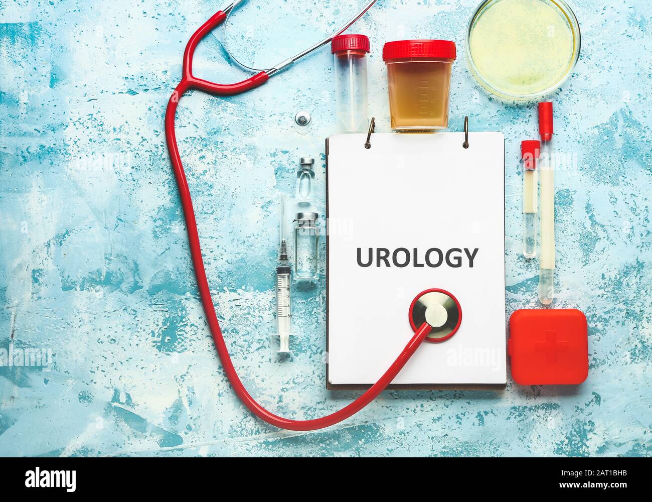 Notebook with text UROLOGY, stethoscope, medicines and urine sample on