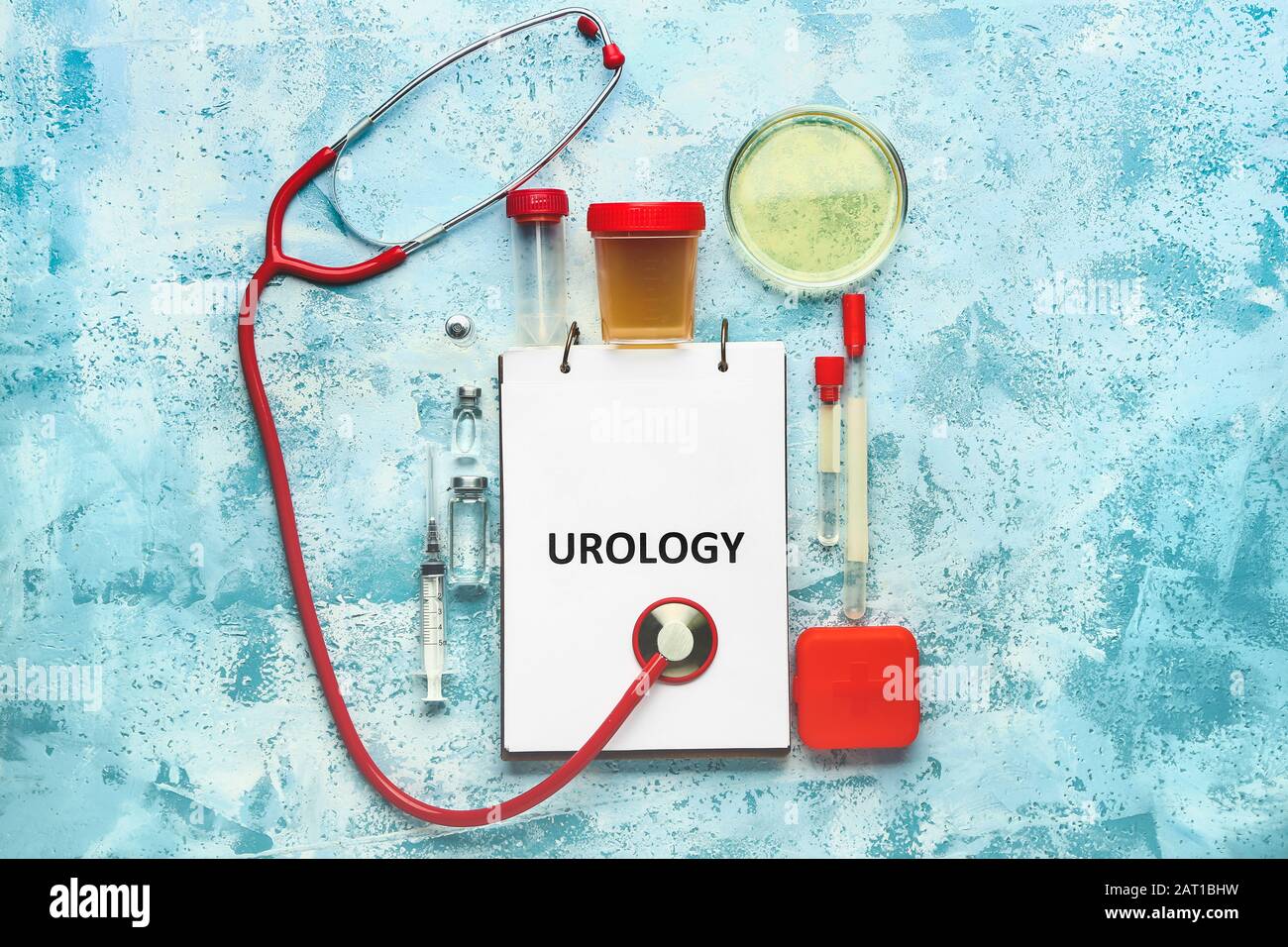 Notebook with text UROLOGY, stethoscope, medicines and urine sample on