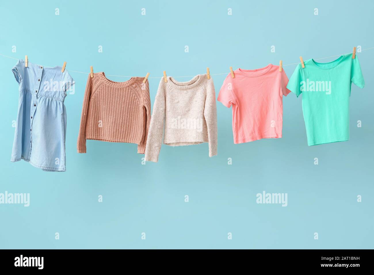 Clean laundry hanging on line against color background Stock Photo