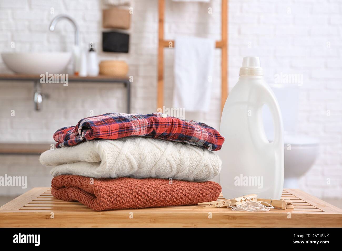 Clean laundry and washing liquid on table in bathroom Stock Photo Alamy
