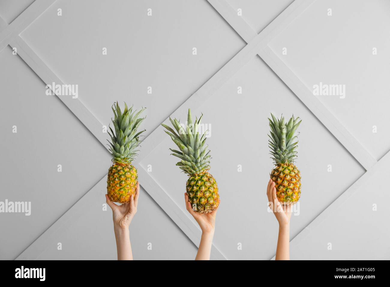 Hands with juicy pineapples on light background Stock Photo