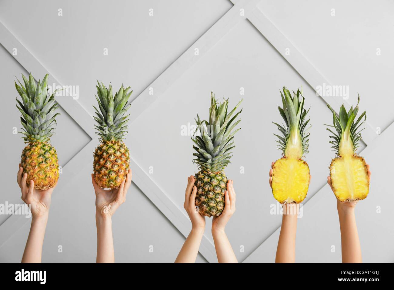 Hands with juicy pineapples on light background Stock Photo
