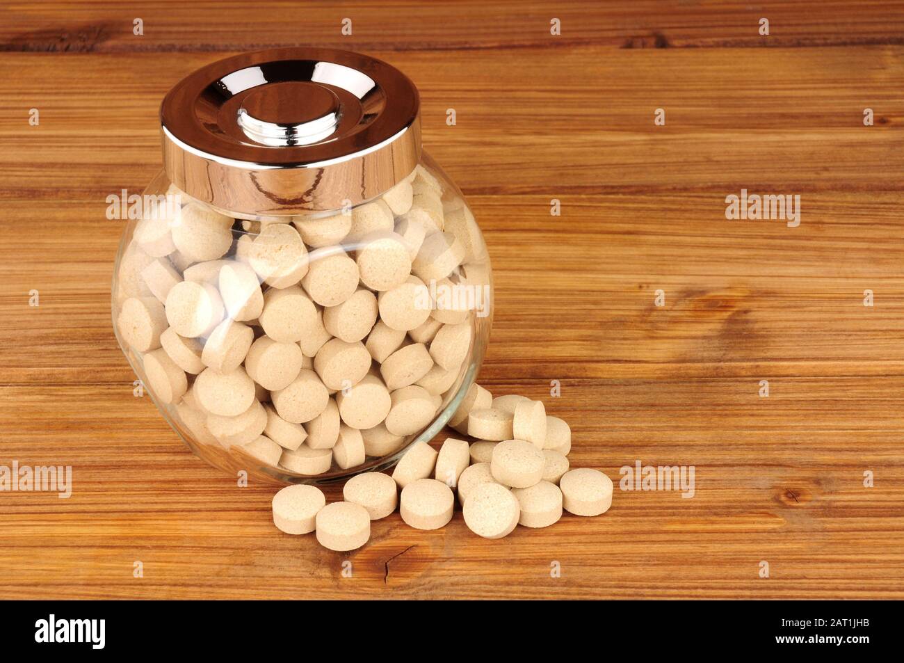 Jar of brewers yeast health tablets on a wooden background Stock Photo