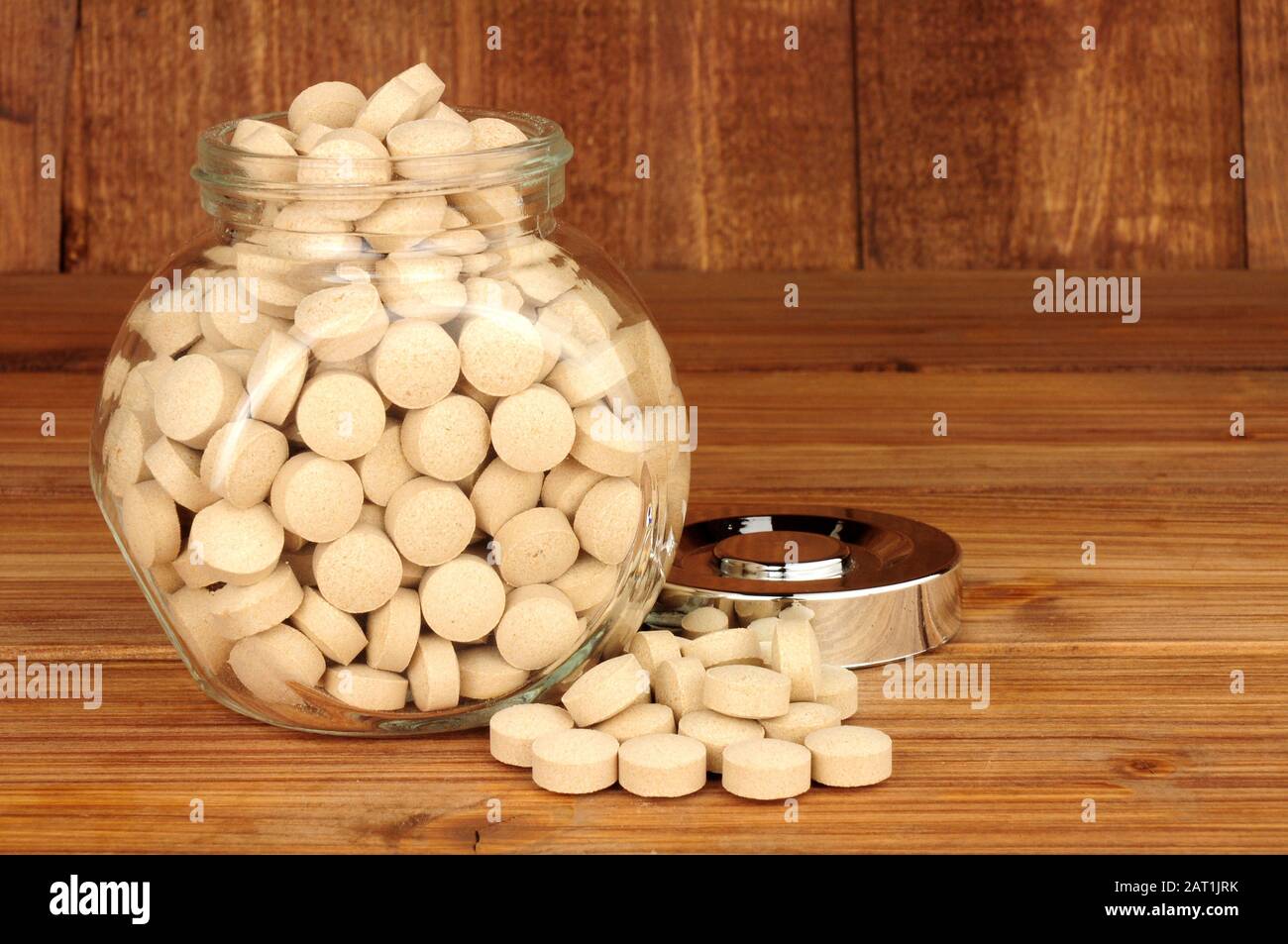 Jar of brewers yeast health tablets on a wooden background Stock Photo