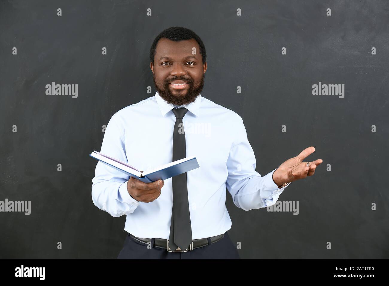 African-American teacher with book near blackboard in classroom Stock ...