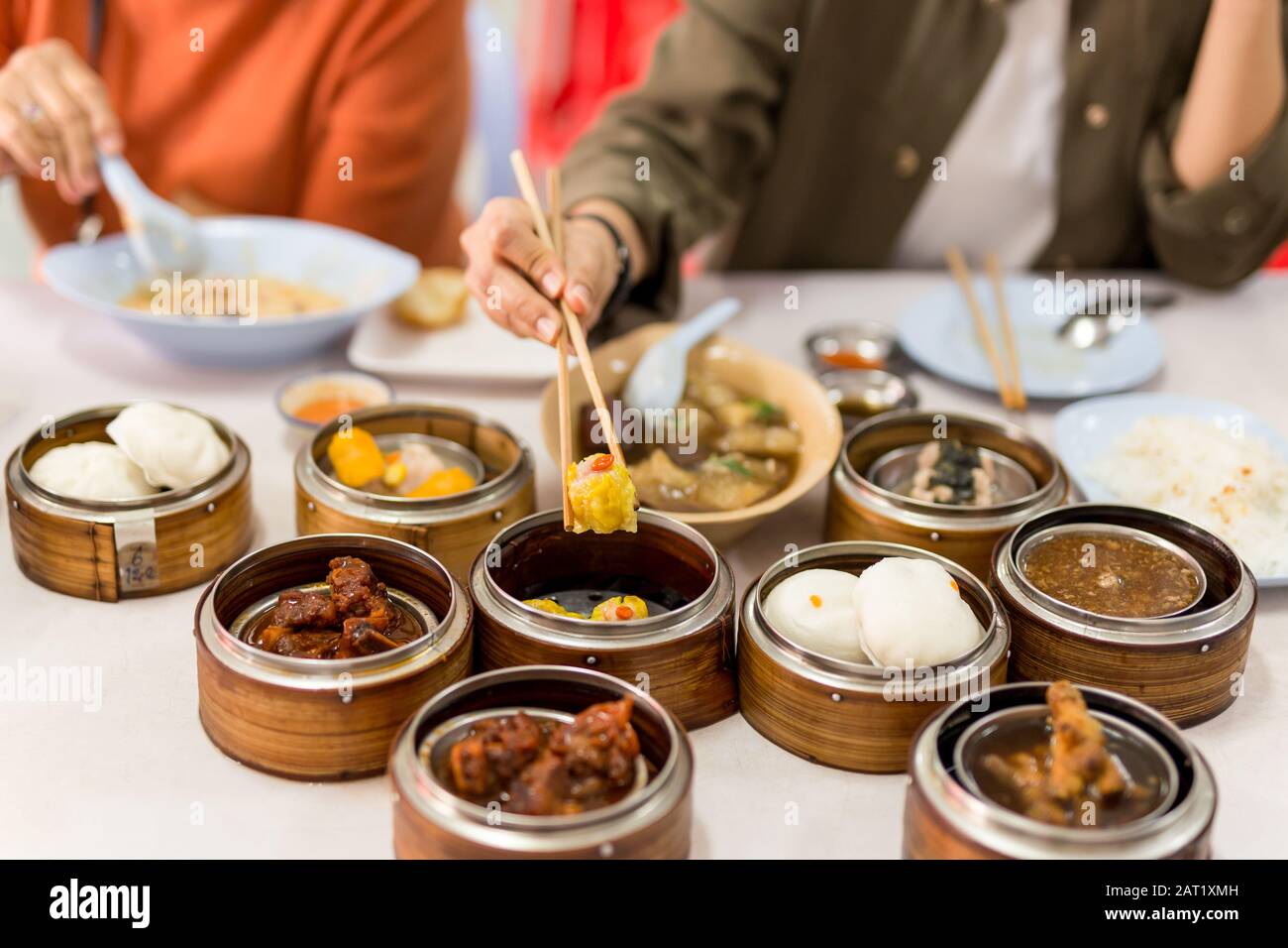 Hand holding chopsticks with steamed dumplings dim sum food in