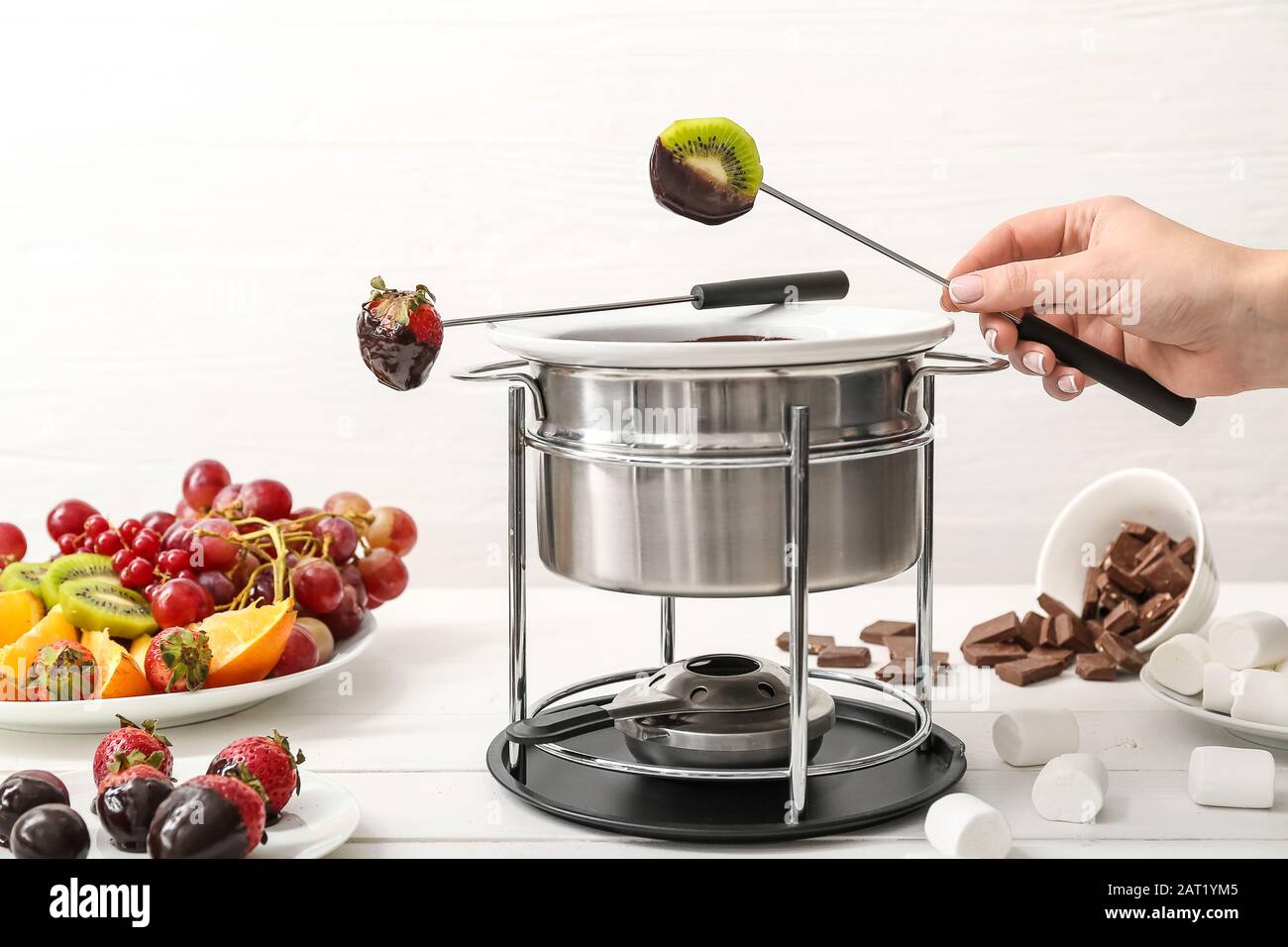 Strawberry on fondue stick and melted chocolate bowl hires stock