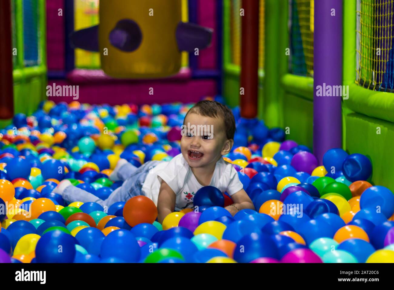 cute and happy little girl laughing and playing in an indoor playground in a shopping mall in Dubai, United Arab Emirates. Stock Photo