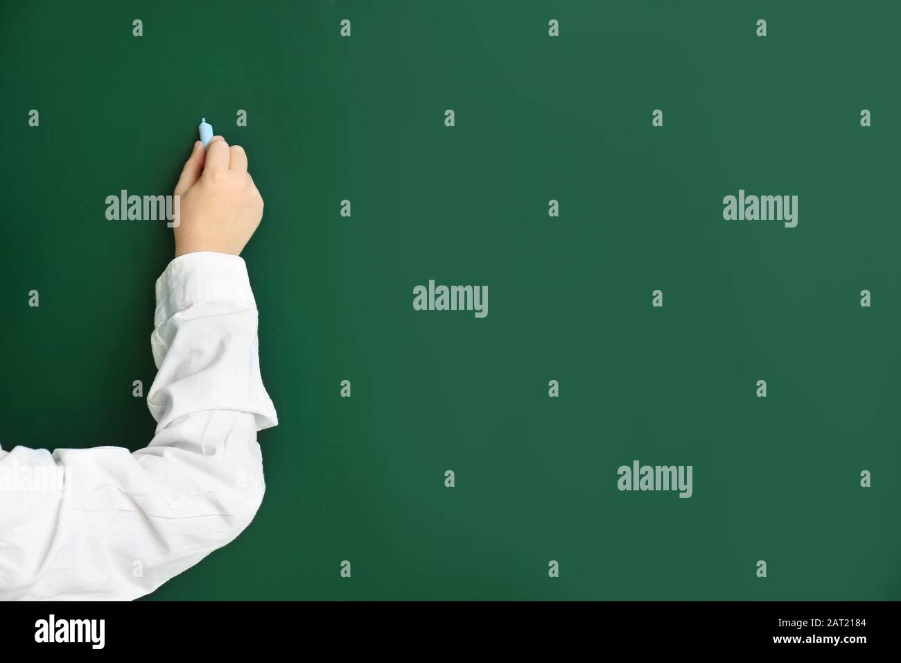 Little schoolboy writing on blackboard in classroom Stock Photo - Alamy