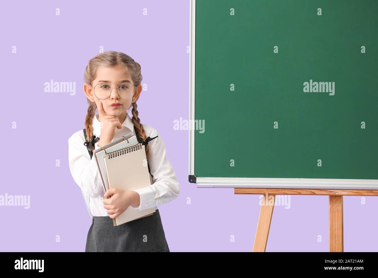 Little schoolgirl near blackboard on color background Stock Photo - Alamy
