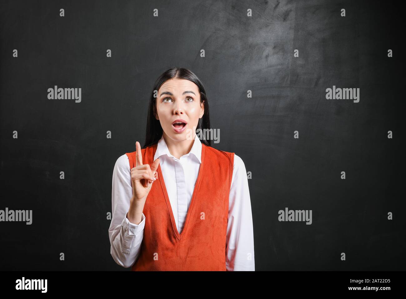 Female teacher with raised index finger near blackboard in classroom Stock Photo