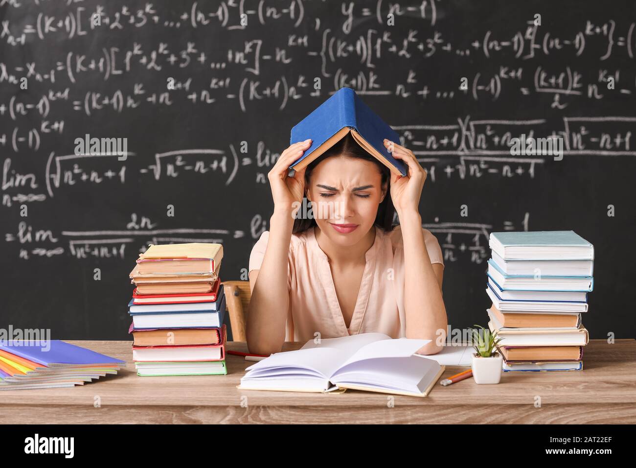 Tired female teacher at table in classroom Stock Photo Alamy