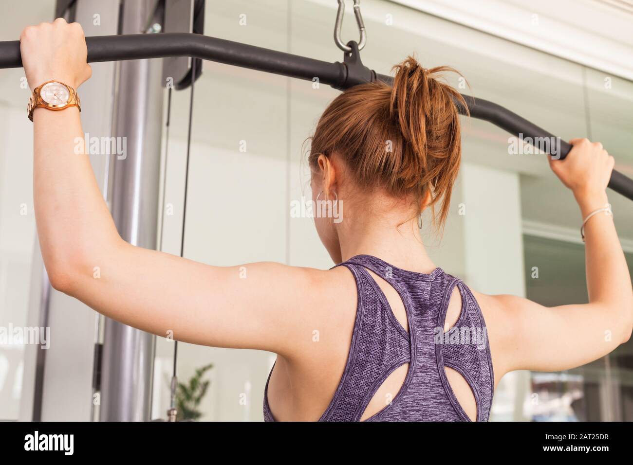 Curly-haired sportswoman performing an upper back exercise Stock