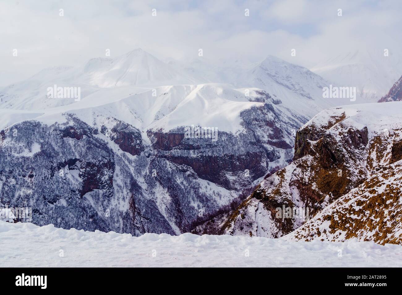 Snow-capped mountain peaks and deep gorges in the area of cross pass, Georgia. Fog, clouds, snow. Stock Photo