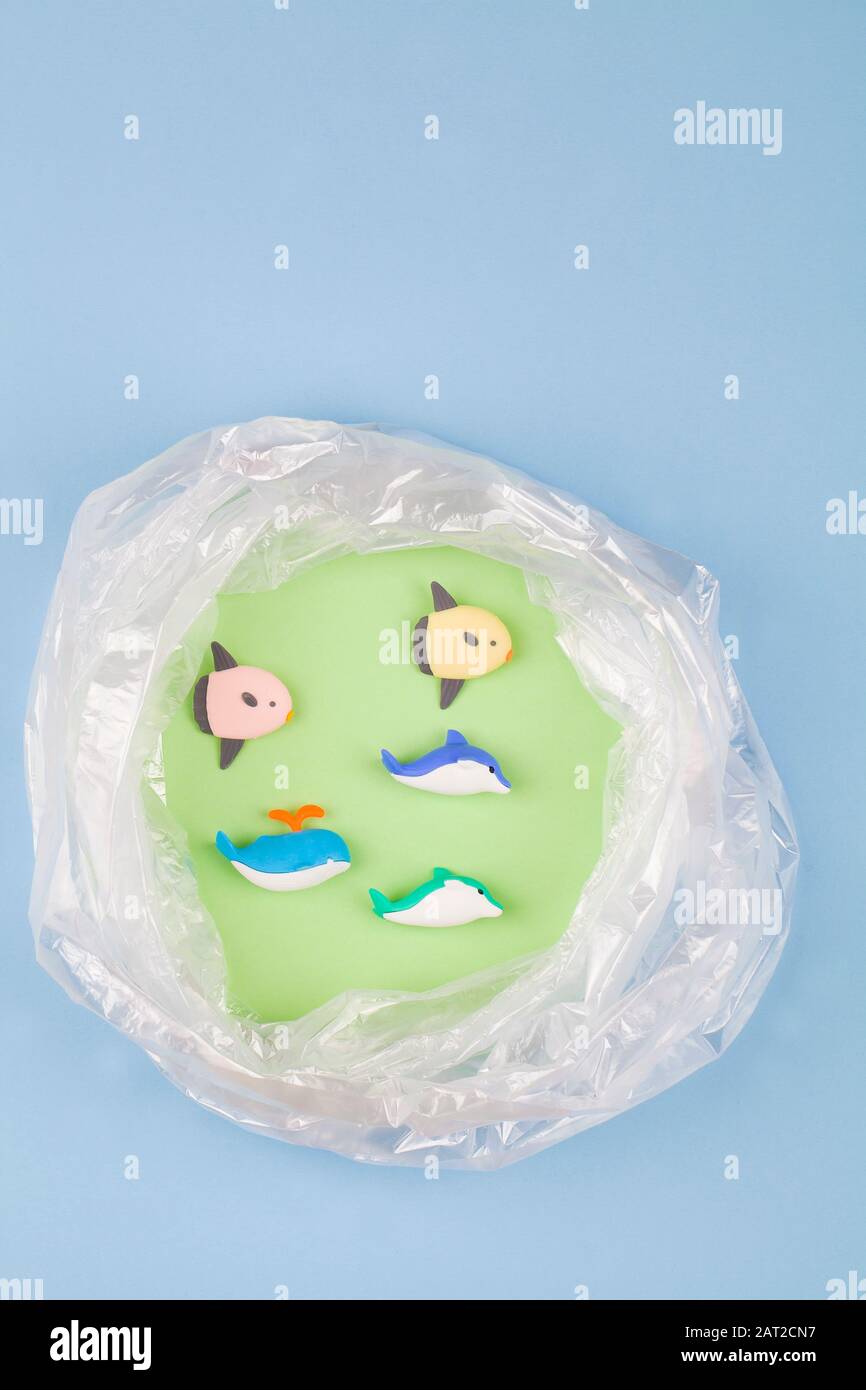 Concept for plastic pollution, environmental pollution, ecology problem. Sea fish and a polyethylene bag. Children's toys. Flat lay, top view Stock Photo