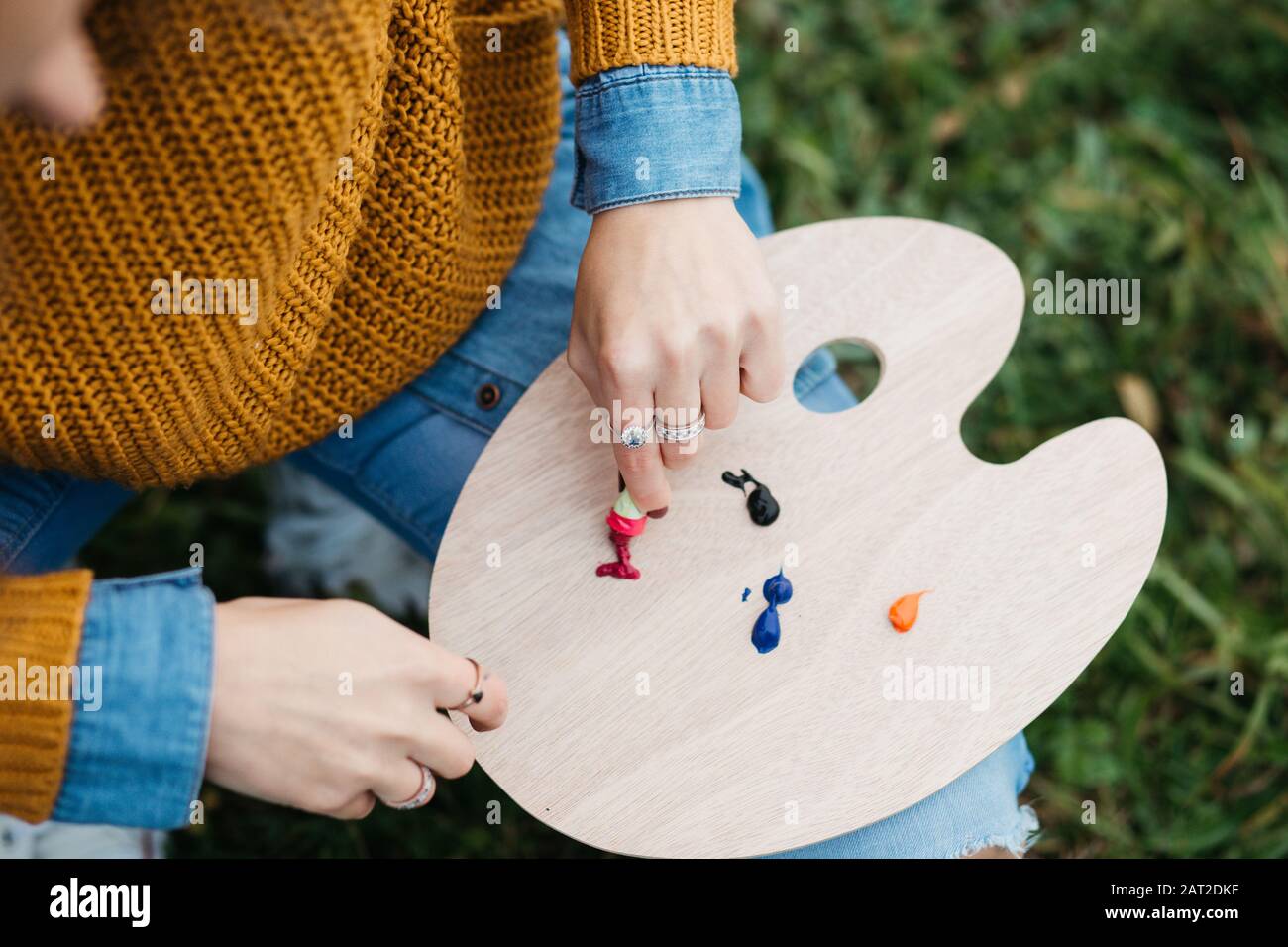 Close up photo of young female artist working on painting outdoors. She