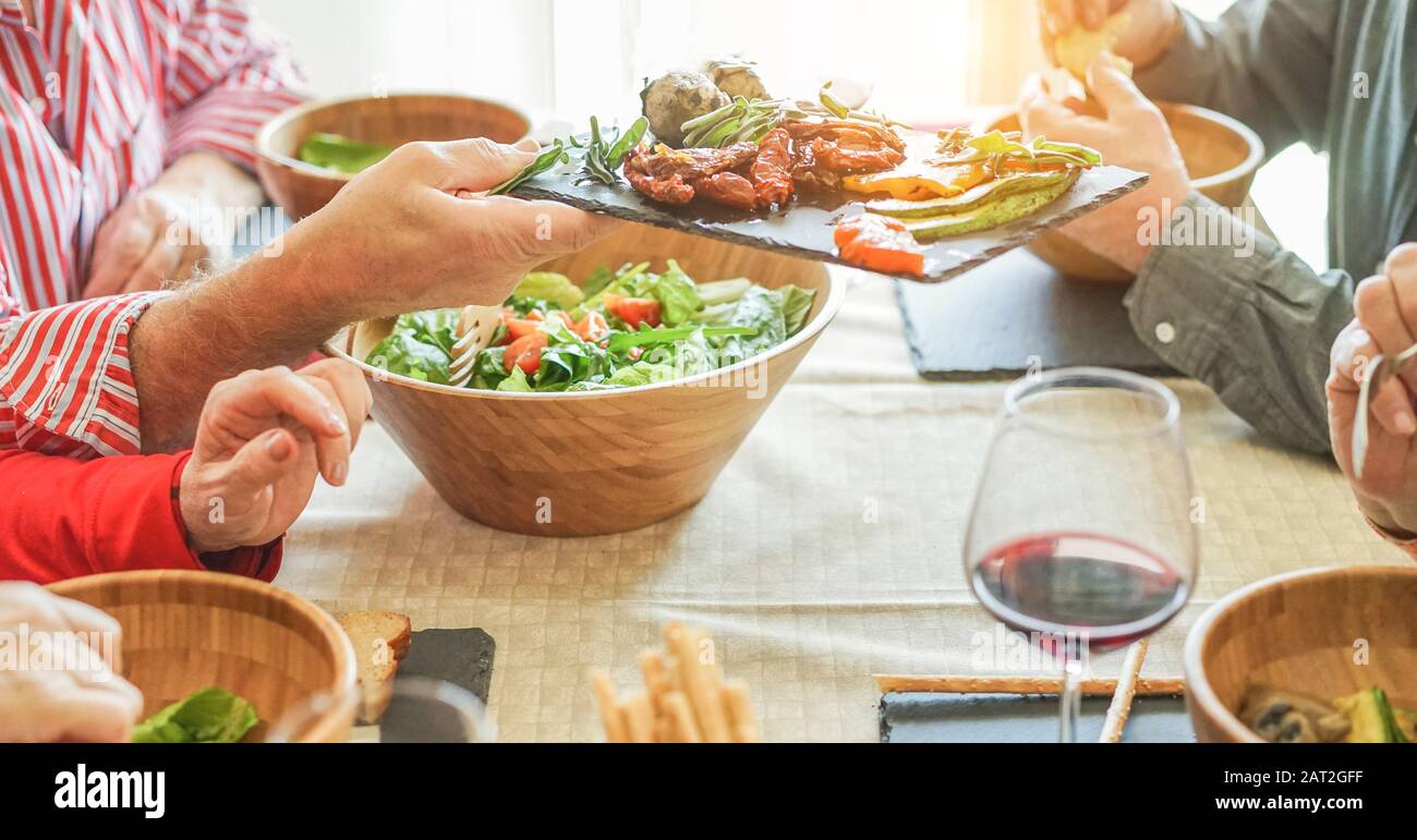 Senior firends having lunch at home - Mature people eating bbq vegetables,fresh salad and drinking red wine - Healthy food and joyful elderly active l Stock Photo