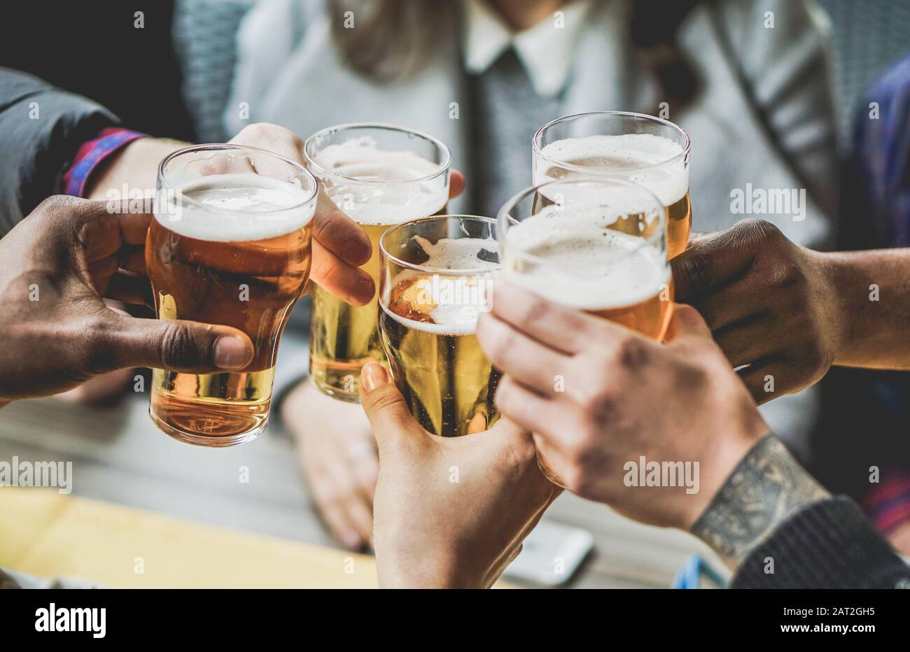 Group of friends enjoying a beer in brewery pub - Young people hands cheering at bar restaurant - Friendship and youth concept - Warm vintage filter - Stock Photo