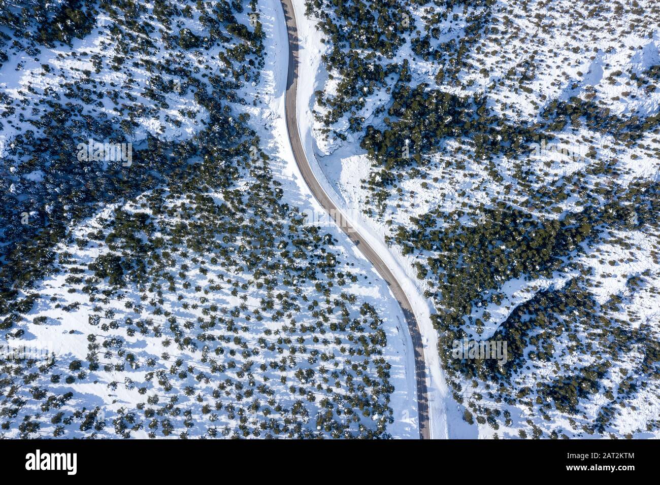 An aerial view of a highway in the forest and mountains with covered ...