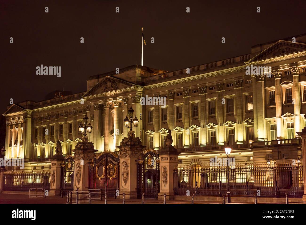 View of famous London landmark Buckingham Palace exterior front facade and royal palace gates, lit up at night on a cold, November evening. Stock Photo