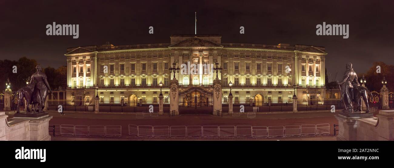 Panoramic, wide view of the spectacular exterior front facade of the queen of England's residence, Buckingham Palace, Westminster, UK lit up at night. Stock Photo