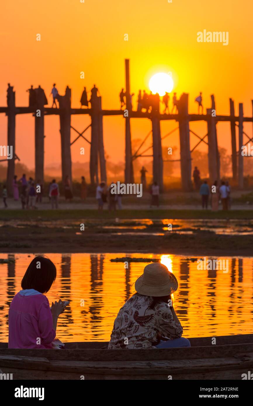 Women in boat on Taungthaman Lake watching the sunset over U Bein ...